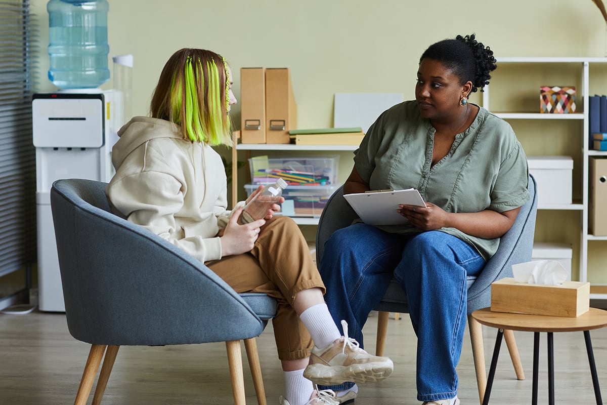 Teenager with green hair speaks with social worker